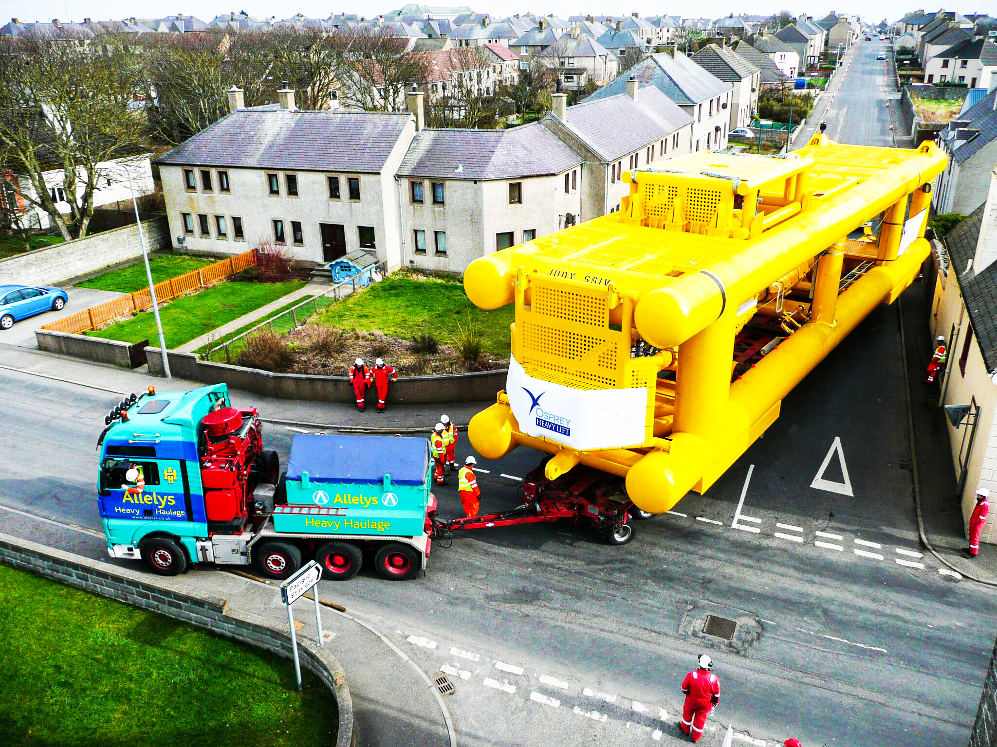 Towheads for subsea oil and gas being skilfully driven through a very small village, with Osprey engineers and project managers overseeing the move.