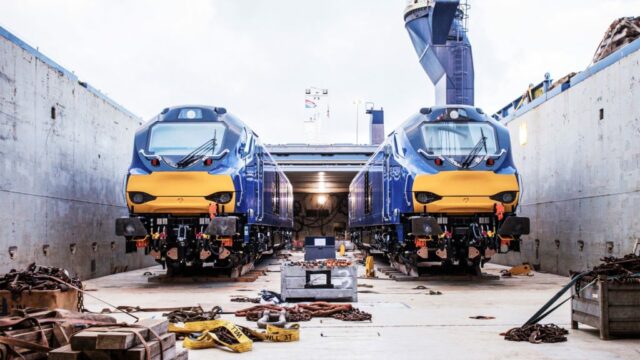 Two trains being loaded into a boat, ready to be shipped to the UK, by Osprey.